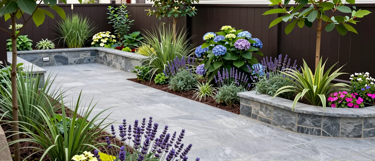 Frisch bepflanztes Gartenbeet neben einer Terrasse mit Lavendel, Hortensien, Straeuchern und Ziergraesern