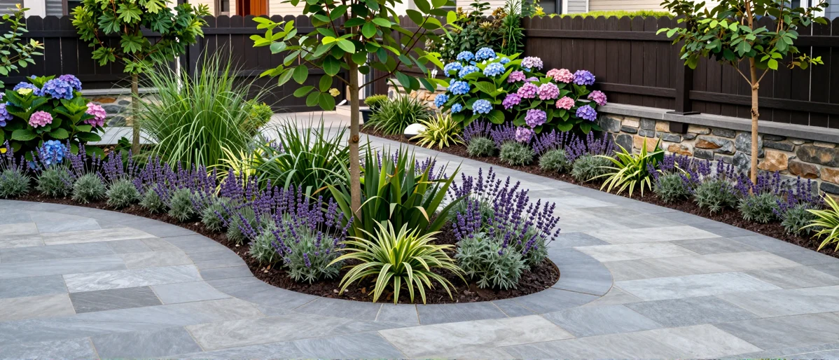 Frisch bepflanztes Gartenbeet neben einer Terrasse mit Lavendel, Hortensien, Straeuchern und Ziergraesern