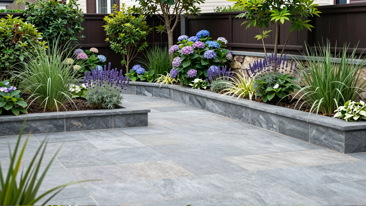 Frisch bepflanztes Gartenbeet neben einer Terrasse mit Lavendel, Hortensien, Straeuchern und Ziergraesern