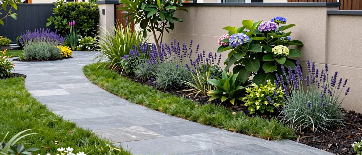 Frisch bepflanztes Gartenbeet neben einer Terrasse mit Lavendel, Hortensien, Straeuchern und Ziergraesern